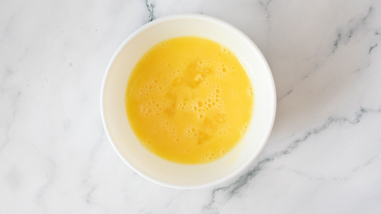 Beaten egg in white bowl