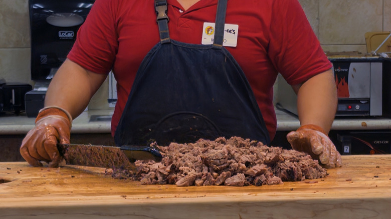 Buc-ee's carver slicing brisket at meat counter.