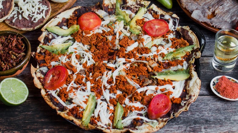 Mexican tlayuda: large tortilla with meat, cabbage, and beans.