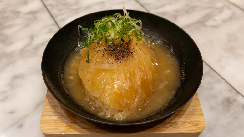 Black bowl of shark fin soup with pepper and green onion