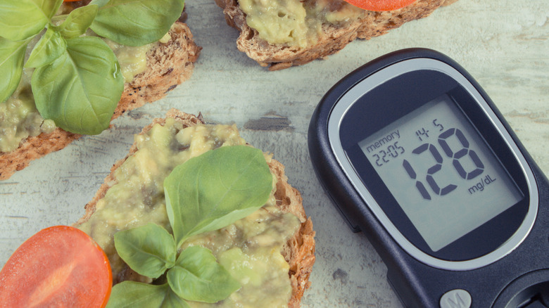 A glucometer and three sourdough slices with avocado and tomatoes