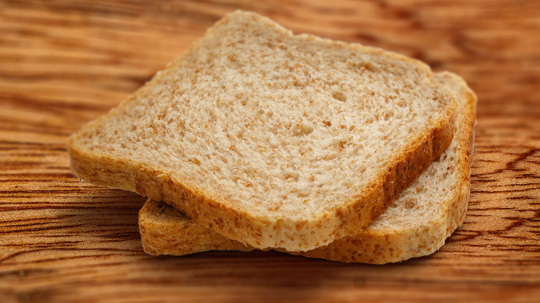 Two slices of whole wheat bread on a wooden board
