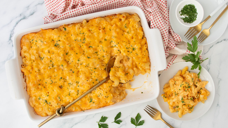 Mac and cheese in casserole dish next to serving on plate