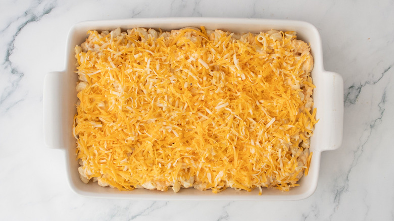 Mac and cheese in casserole dish with shredded cheese on top