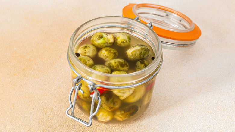 Open jar of Brussels sprouts in liquid with spices
