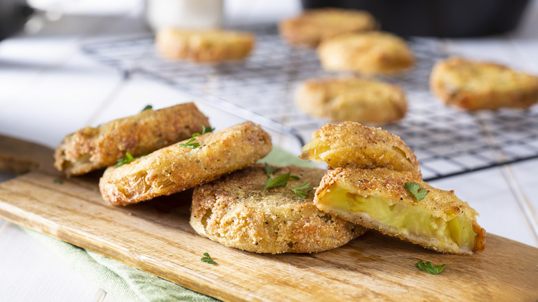 Several fried green tomatoes on a cutting board.