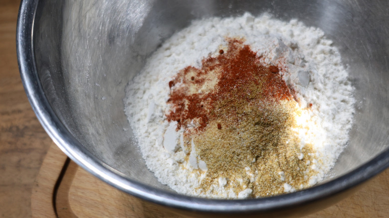 metal mixing bowl with flour and spices in it