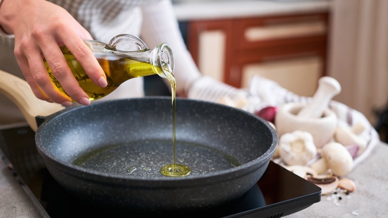 hands pouring olive oil into pan