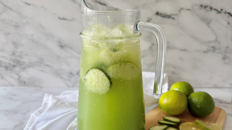 Sparkling cucumber limeade in pitcher with limes in background
