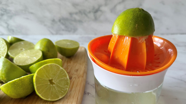 Lime half on juicer with more limes on wooden board
