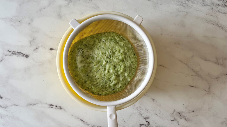 Blended cucumber mixture in sieve over bowl