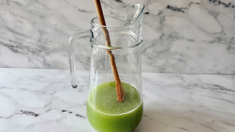 Pitcher with green liquid and wooden spoon