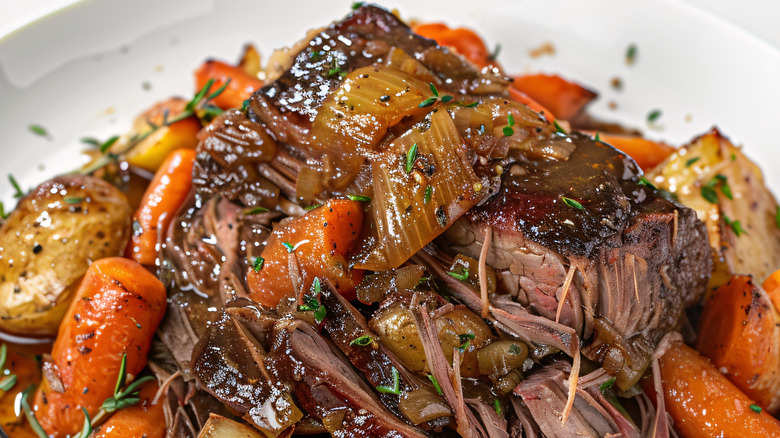 A plate of pot roast with potatoes and carrots.