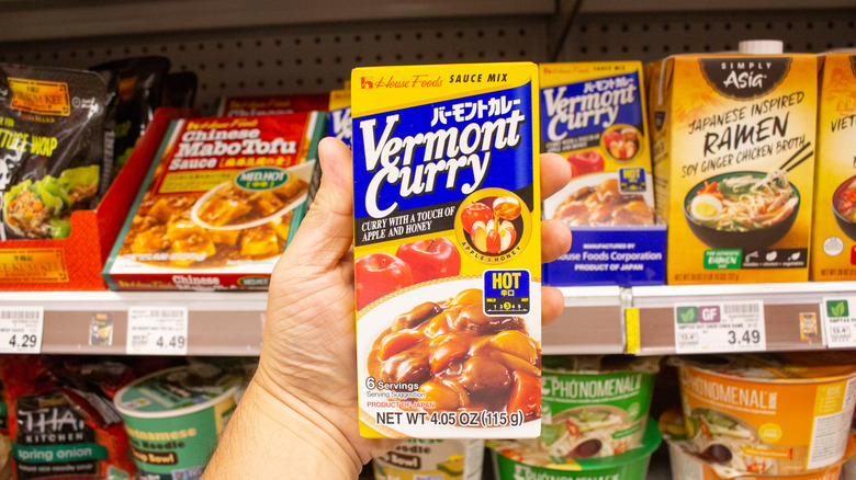 A hand holding up a container of Vermont Japanese curry.