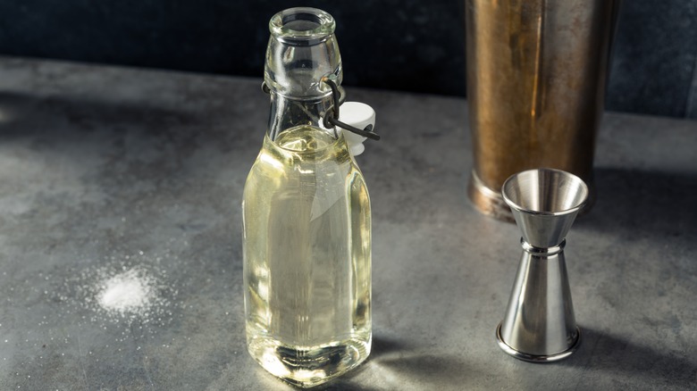 Simple syrup and cocktail jigger on grey table