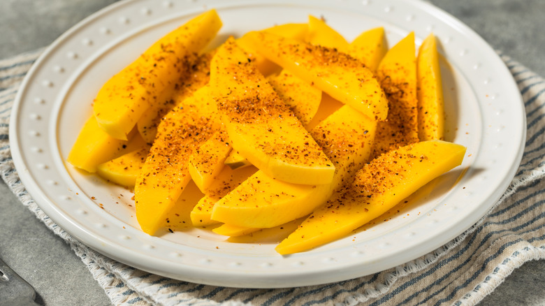 Sliced mango with chili-lime powder on white plate.