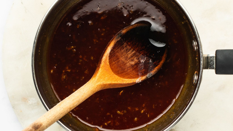Sriracha honey sauce in saucepan with wooden spoon