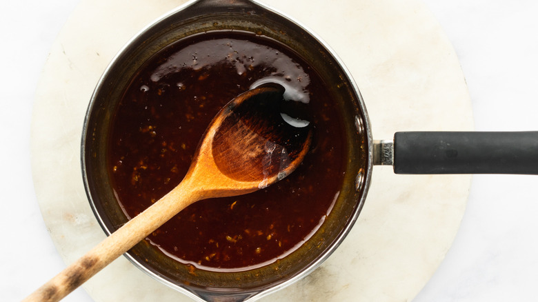 Honey sriracha sauce in saucepan with wooden spoon
