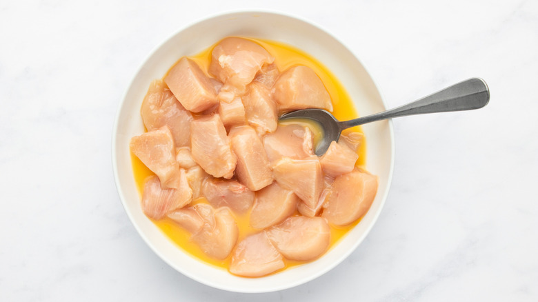 Diced chicken breast and beaten egg in white dish with spoon