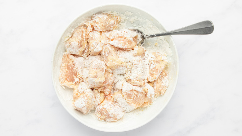 Diced chicken breast tossed with cornstarch in white dish