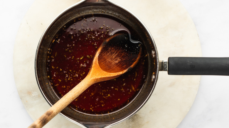 Honey sriracha sauce in saucepan with wooden spoon