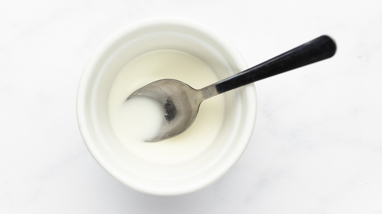 Cornstarch and water mixture in small white bowl with spoon