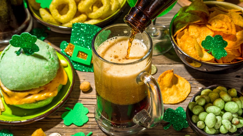 A beer being poured next to St. Patrick's Day foods