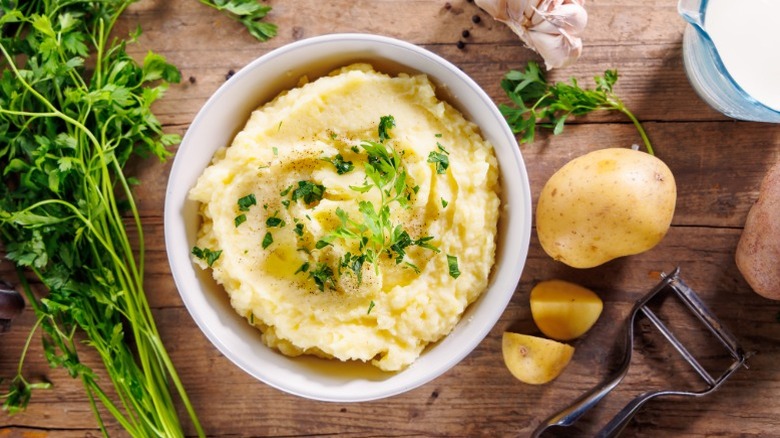 Mashed potatoes and ingredients on a wooden board