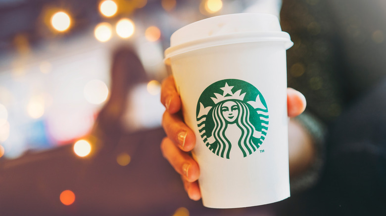 Person holding a Starbucks cup in front of lights