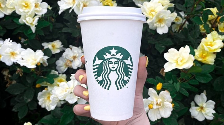 starbucks cup with flowers in background