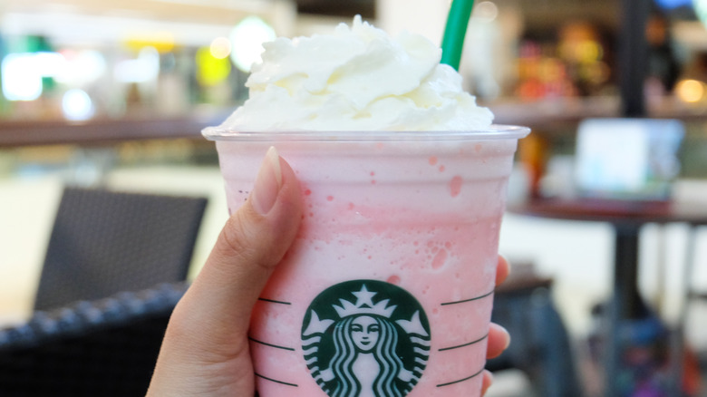 A pink Starbucks frappucino topped with whipped cream