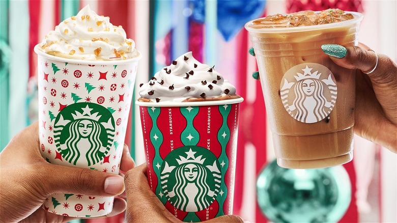 people holding Starbucks holiday cups