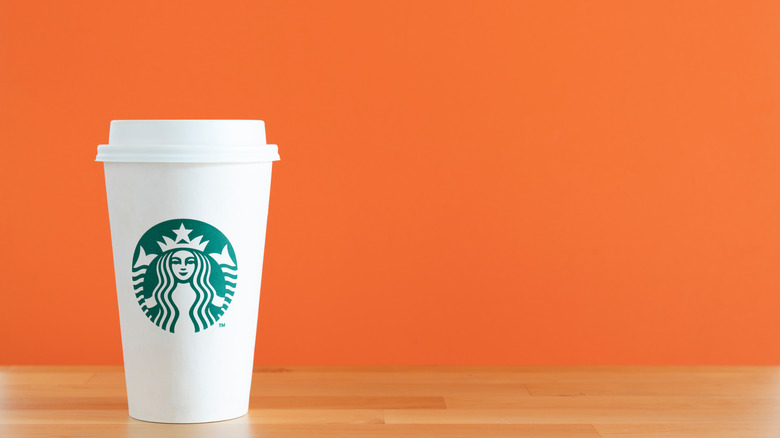 A Starbucks cup against an orange backdrop