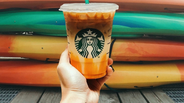 Person holding caramel macchiato near boats