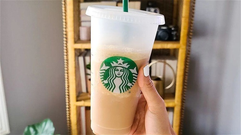 Hand holding Starbucks drink in plastic cup