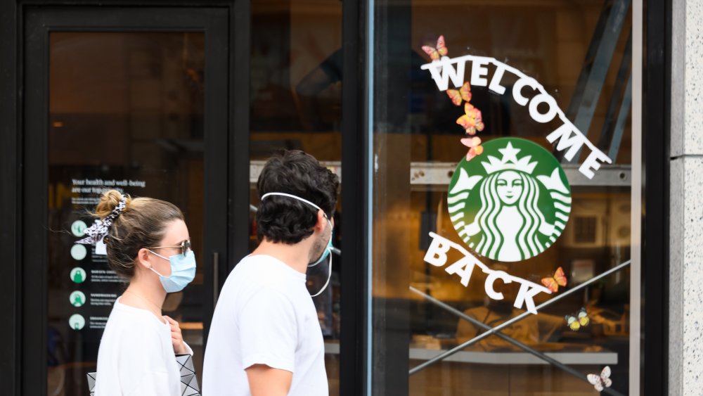 Masked couple walking by Starbucks