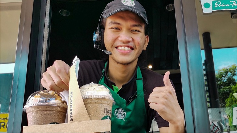 Starbucks worker gives thumbs up and hands out drinks