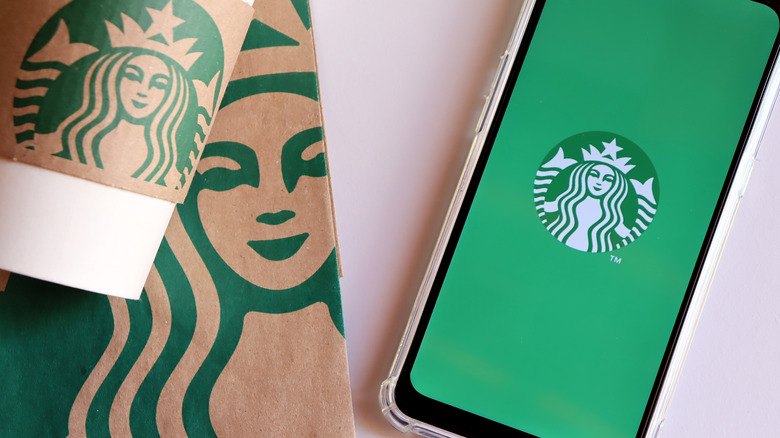 Starbucks logo on a cup, a paper bag, and the app on a cell phone 