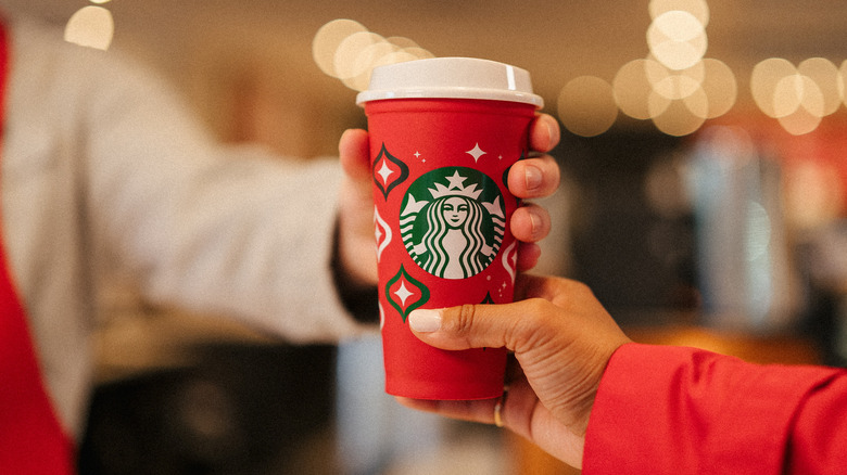 barista handing customer red cup