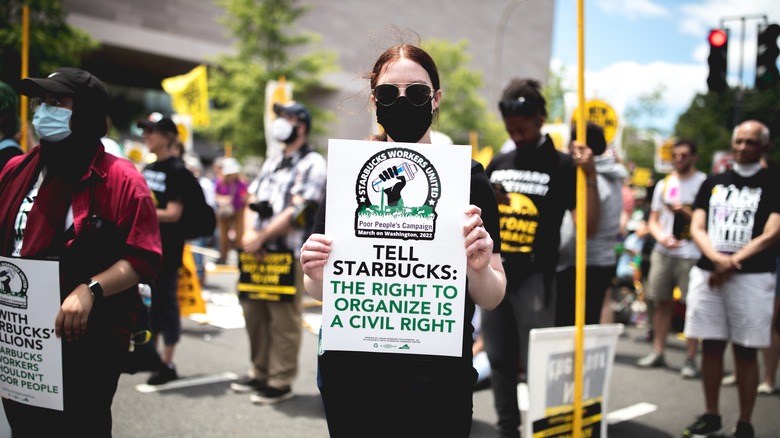 Protestor holding sign that reads "Tell Starbucks: The right to organize is a civil right"