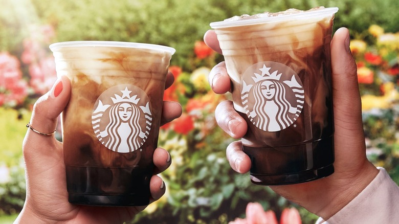 hands holding Starbucks drinks