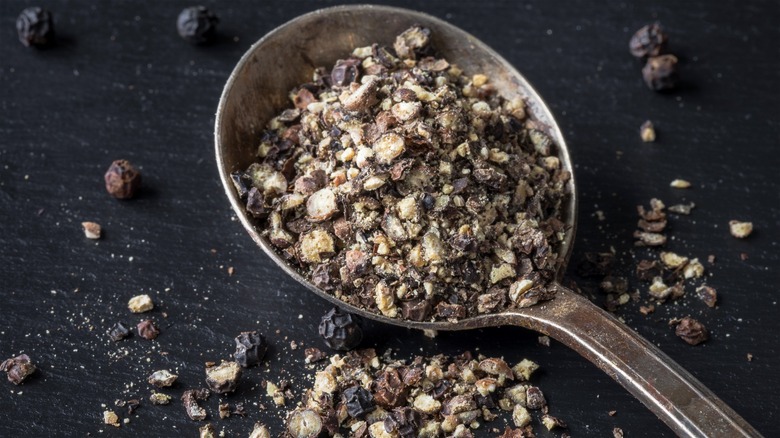 Coarsely ground black pepper on a metal spoon.