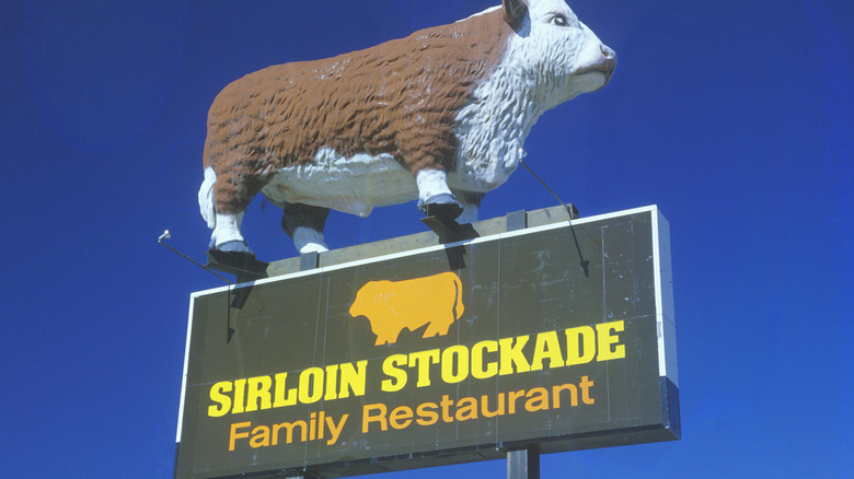 Sirloin Stockade sign with a full-size cow statue atop it
