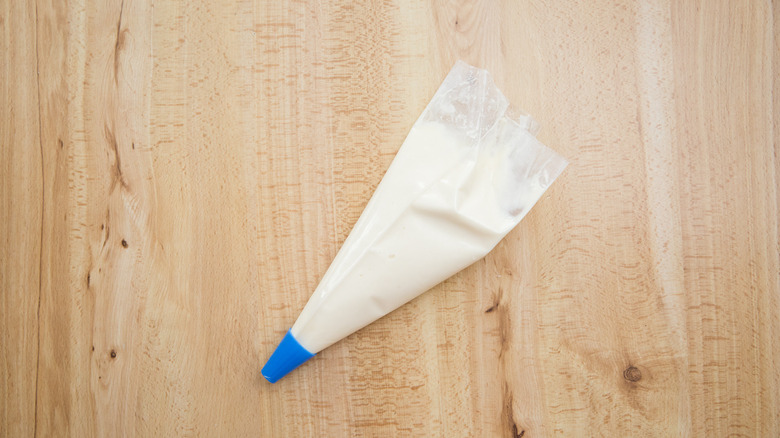 piping bag filled with frosting on wooden table