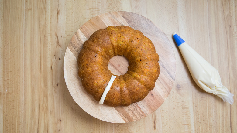 partially iced bundt cake on stand
