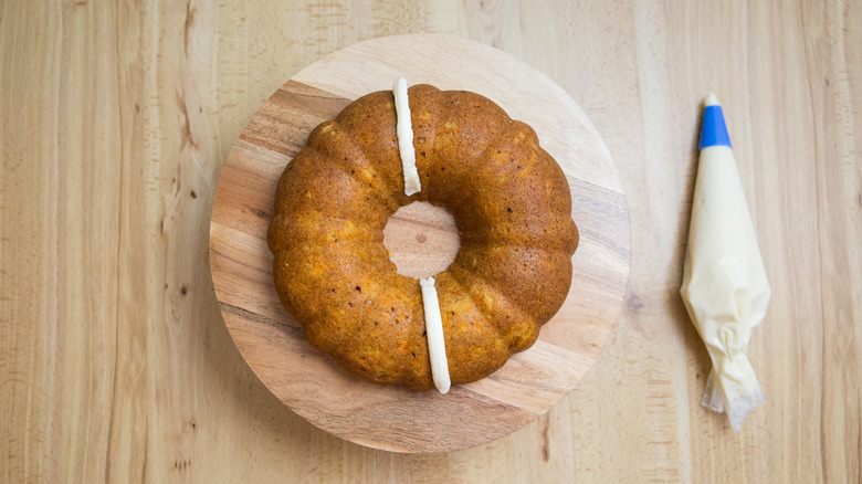 partially iced bundt cake on stand