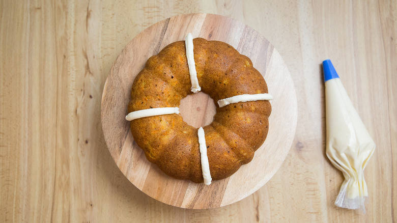 partially iced bundt cake on stand