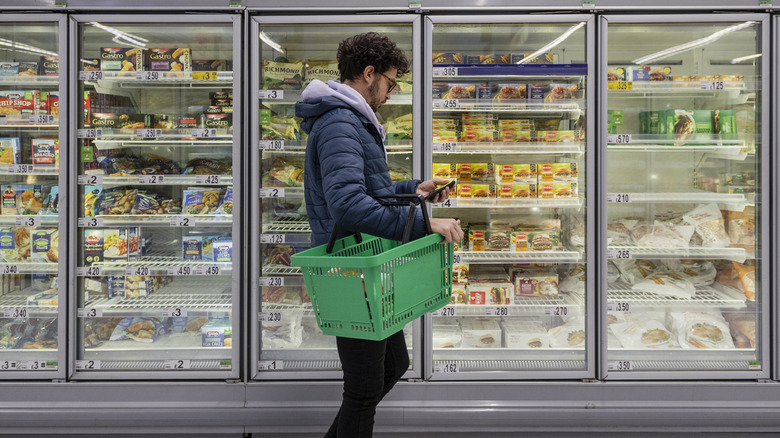 man shopping in frozen food section of a grocery store