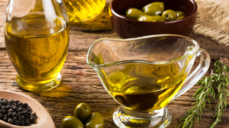 Glass boat of olive oil on table