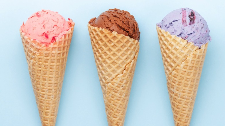 Three ice cream cones in a row on a light blue background
